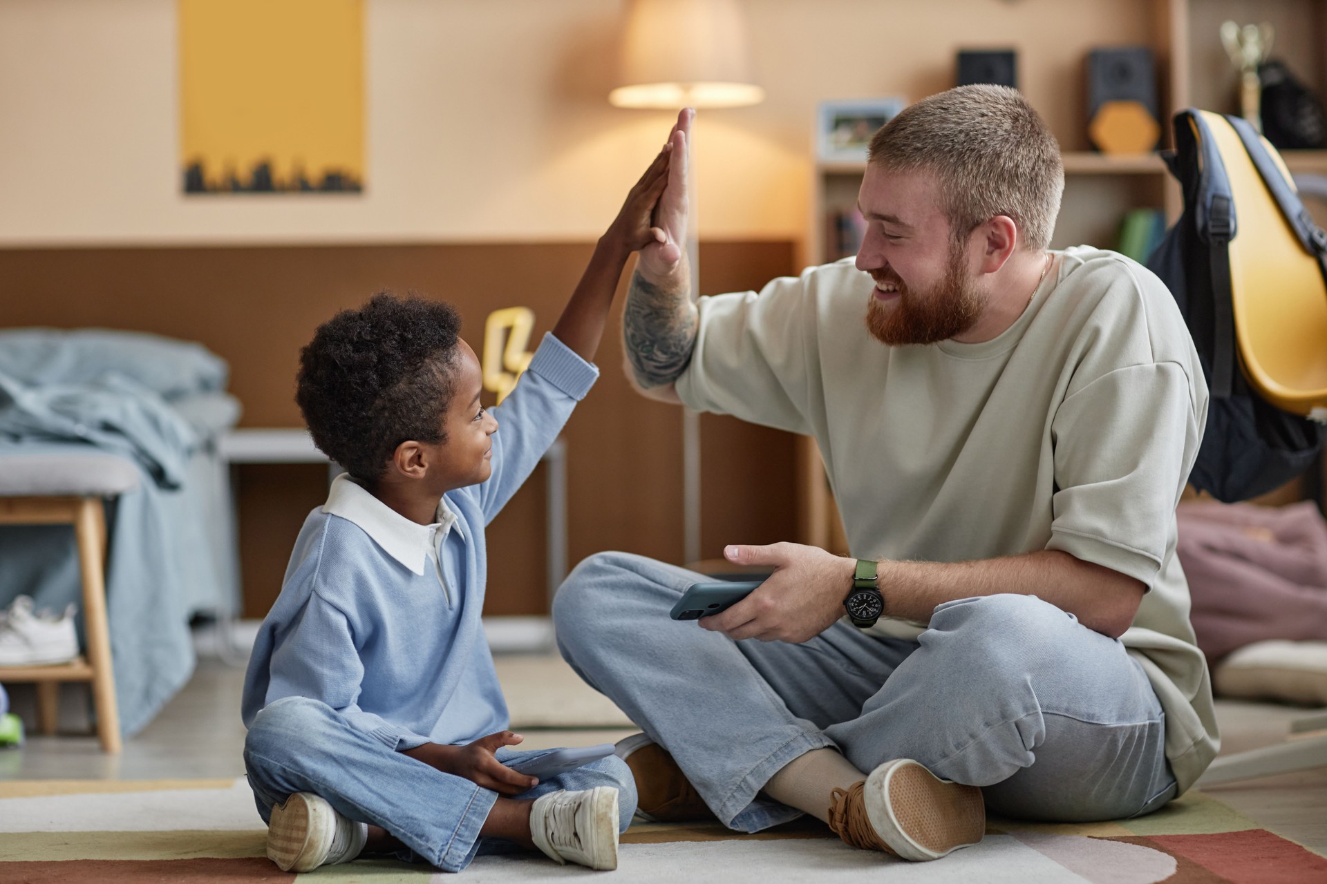 Preschool Adopted Black Boy Giving High Five to Smiling Dad Rejoicing at Game Win Indoors